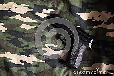 Black handgun on military camouflage green, brown, beige and black fabric Stock Photo