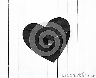 Black Heart representing Evil or Disease on White Wood Board Background with copy space. A horizontal photo Stock Photo