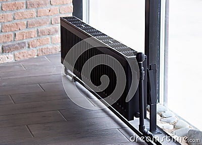 Black heating battery near the window in winter heats the room, the house Stock Photo