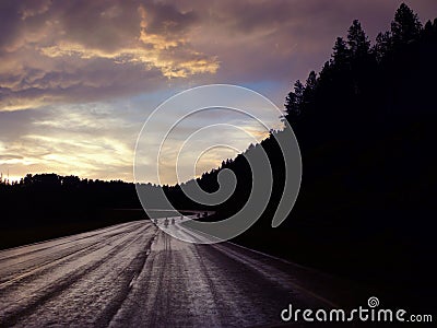 Black Hills motorcyclists ride at sunset on wet road Stock Photo