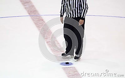 Black hockey puck and referee legs on ice rink. Winter sport Stock Photo