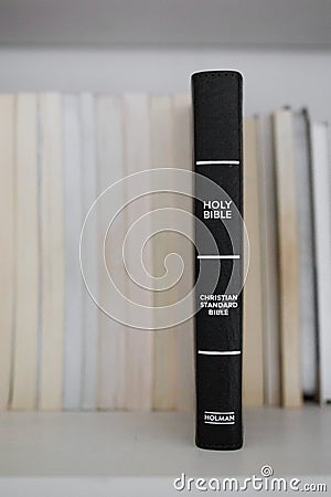 Black Holy Bible on Book Shelf Among Other Books Editorial Stock Photo