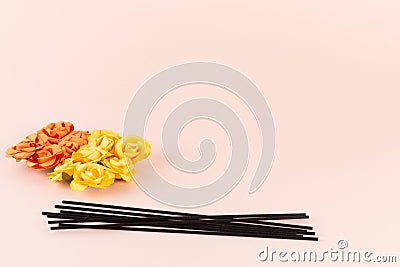 Black incense sticks with orange and yellow flowers on pink background Stock Photo