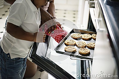 Black kid helping mom baking cookies in the kitchen Stock Photo