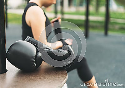 Black leather boxing gloves on the background of athletic girl shakes boxing bandages on hands before training Stock Photo