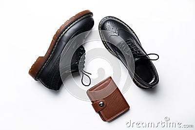 Black leather derby shoes with polyurethane soles and a brown purse with a button on a white background Stock Photo