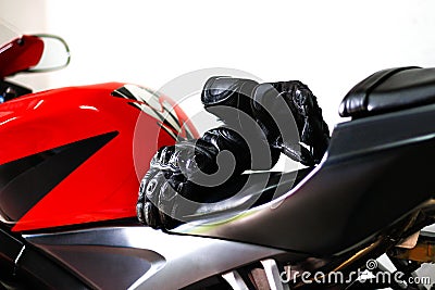 Black leather motorcycle gloves is lying on a red sports bike. Stock Photo