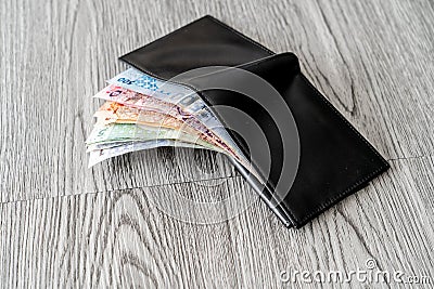 Black leather wallet with Qatari Riyals spread out Stock Photo