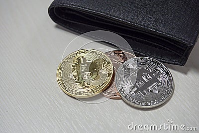 Black leather wallet on table with coins of bitcoins falling out of their pockets. The concept of crypto currencies Stock Photo