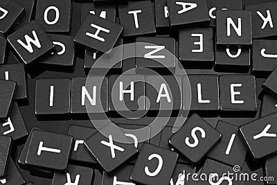 Black letter tiles spelling the word & x22;inhale& x22; Stock Photo