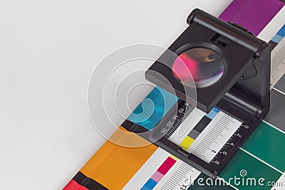 Black magnifying glass standing on the test print with colored background. Print loupe on offset printed sheet with basic colors Stock Photo