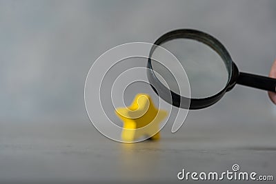 A black magnifying glass with a yellow star. The concept of finding the star, find a new actor. Hiring and recruitment selection Stock Photo