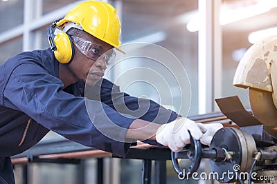 Black male african american workers wear sound proof headphones and yellow helmet working an iron cutting machine in background Stock Photo