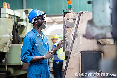 Black Male Engineer Working on machine in Factory. black man engineer checking Quality control the condition of the machine. Stock Photo