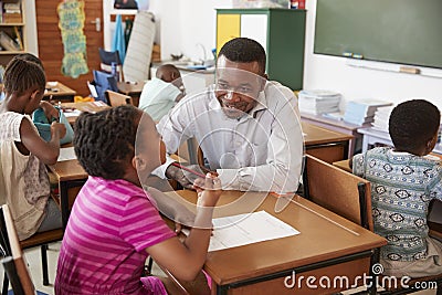 Black male teacher helping elementary school girl in class Stock Photo