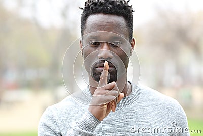 Black man asking for silence with finger on lips Stock Photo