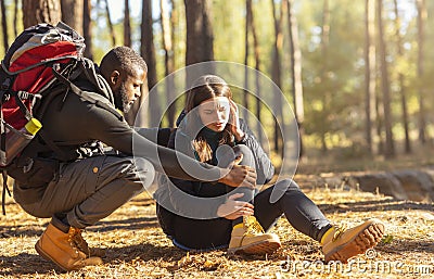 Black man comforting his injured woman, hiking together Stock Photo