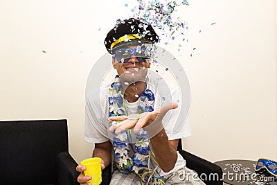 Black man is dressed as a captain or pilot, wearing a cap. Brazilian throws confetti to the top.. Stock Photo