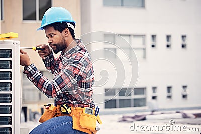Black man, electrician and maintenance with engineering and ac repair with handyman working with tools on roof. Fix air Stock Photo