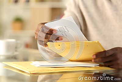 Black man hands opening a padded envelope at home Stock Photo