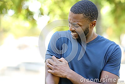 Black man scratching itchy arm in a park Stock Photo