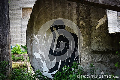 Black man sitting in concrete building block drawing graffiti Editorial Stock Photo