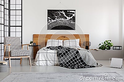 Black map on white wall above wooden headboard in simple bedroom interior Stock Photo