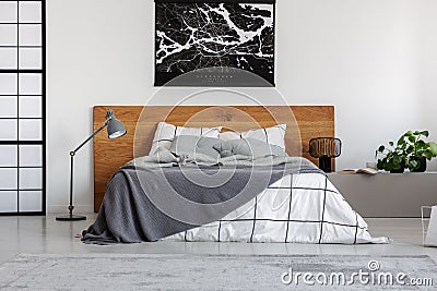 Black map on white wall above wooden headboard in simple bedroom Stock Photo