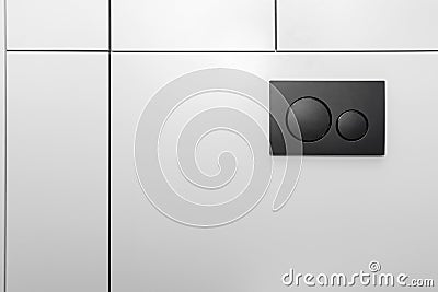 Black matt toilet flush with two round buttons placed in the wall of a restroom lined with a wooden panel. Stock Photo