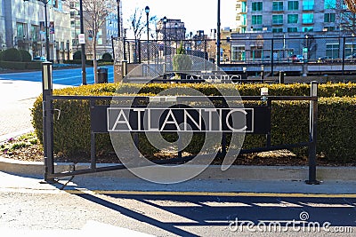 A black metal gate with the word `Atlantic` on the front surrounded by street cones a red curb and black building Stock Photo