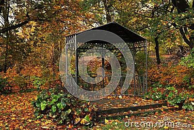 Black metal gazebo and yellowed trees in park Stock Photo