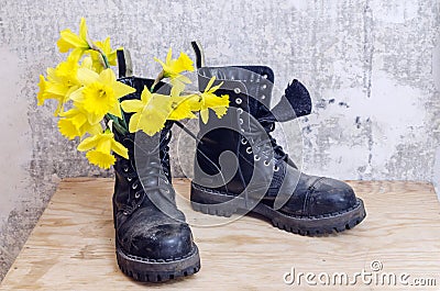Black military muddy shoes with yellow narcissus Stock Photo