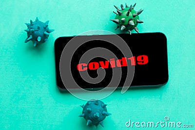Black mobile screen with inscription COVID19 and viruses on green background. Stock Photo