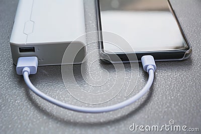 Mobile smart phones charging with power bank on desk. Stock Photo