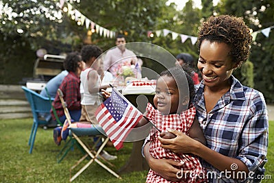 Black mother and baby holding flag at 4th July garden party Stock Photo