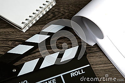 Black movie clapper with script sheets and notebook on a wooden table Stock Photo