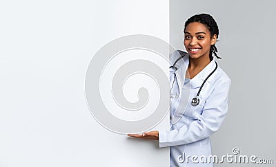 Black muslim female doctor pointing at white advertisement board, presenting something Stock Photo