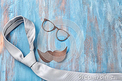 Black mustache, glasses and tie on color wooden background. Happy Father's Day celebration Stock Photo