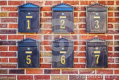 Black numbered mailboxes on brick wall at apartment building Stock Photo