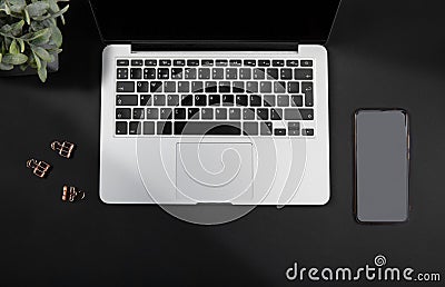 Black office desk with laptop, smartphone and flowers Stock Photo