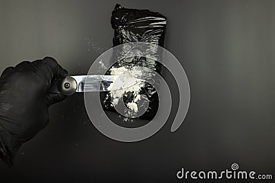 Black packet cut with a knife, white powder-hand with a knife Stock Photo