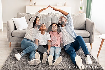 Black parents making symbolic roof of hands above children Stock Photo