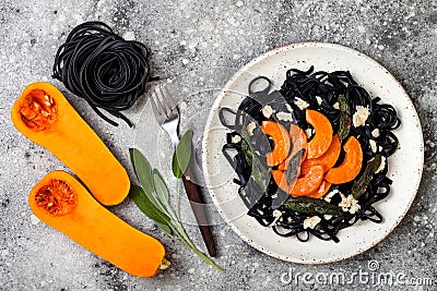 Black pasta with roasted butternut squash, parmesan cheese and fried sage. Halloween black and orange party dinner concept Stock Photo