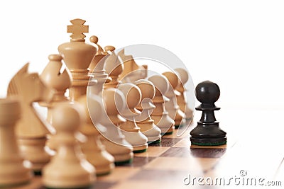 Black pawn challenging army of white chess pieces Stock Photo