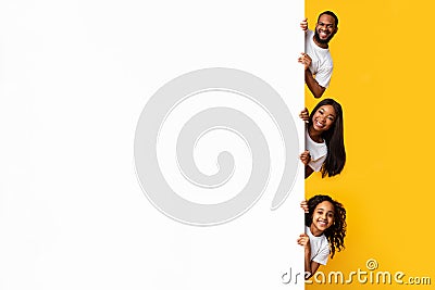 Black people peeking out blank white advertising billboard at studio Stock Photo