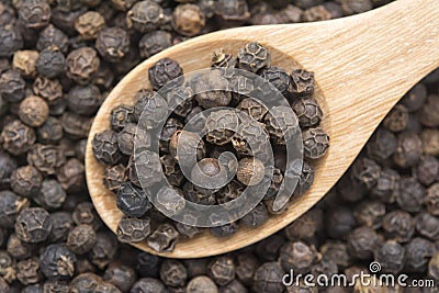 Black peppercorns on wooden spoon Stock Photo