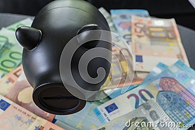 Black piggy bank on pile of Euro banknotes as financial saving c Stock Photo