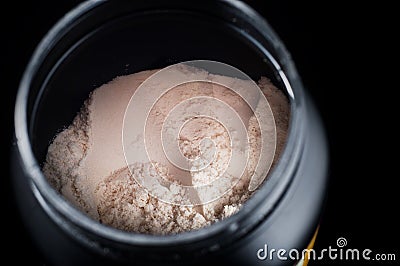 Black plastic jar with a sports supplement protein. On a black background Stock Photo