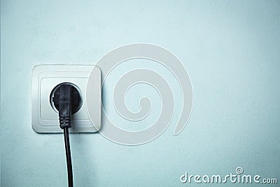Black plug inserted in electrical outlet. Stock Photo