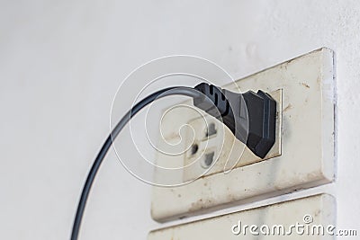Black plugs are plugged into an old outlet Stock Photo